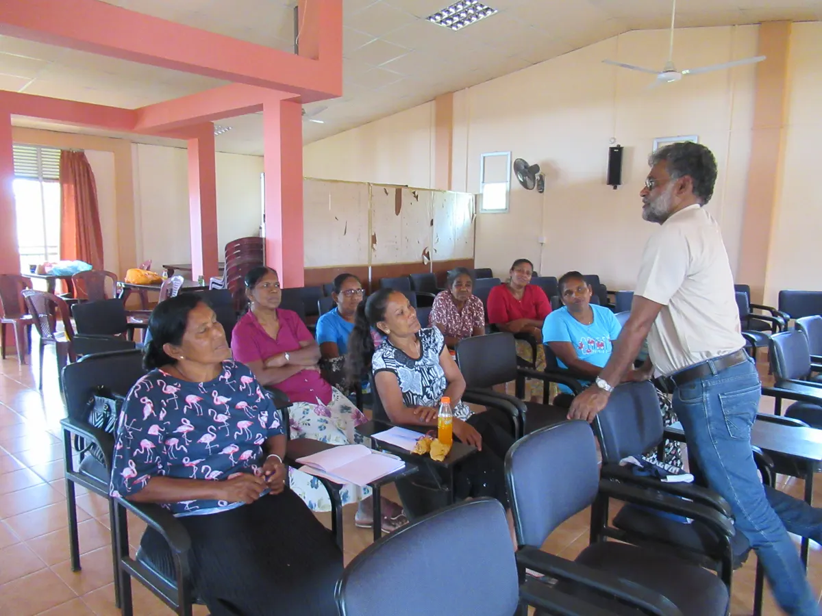 A facilitator addressing women fish processors in a hall